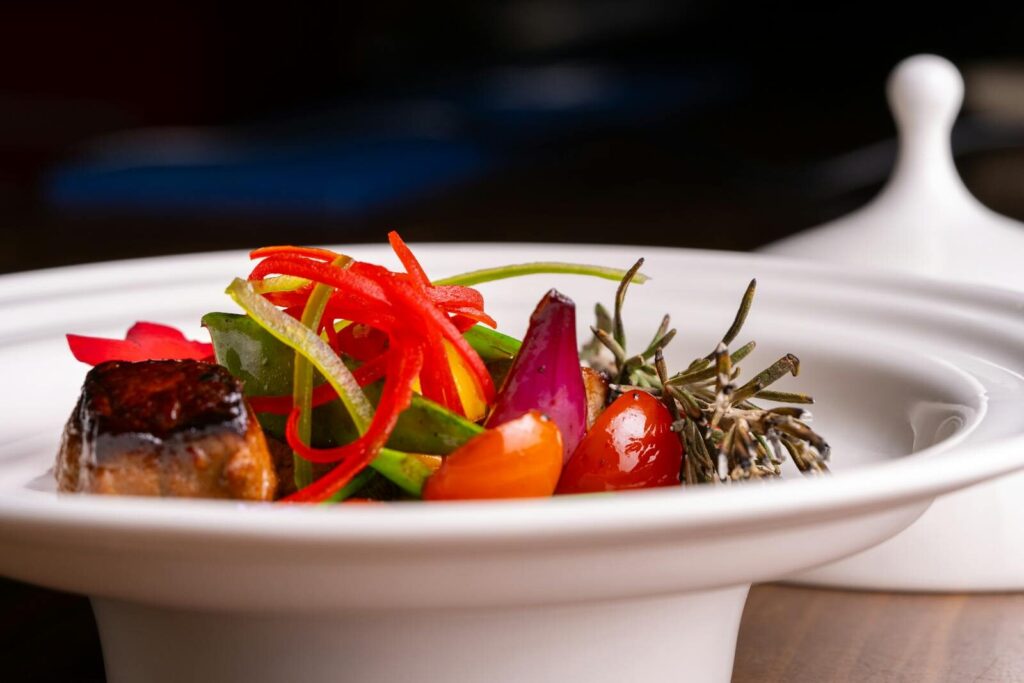A vibrant gourmet dish featuring assorted vegetables elegantly plated indoors.