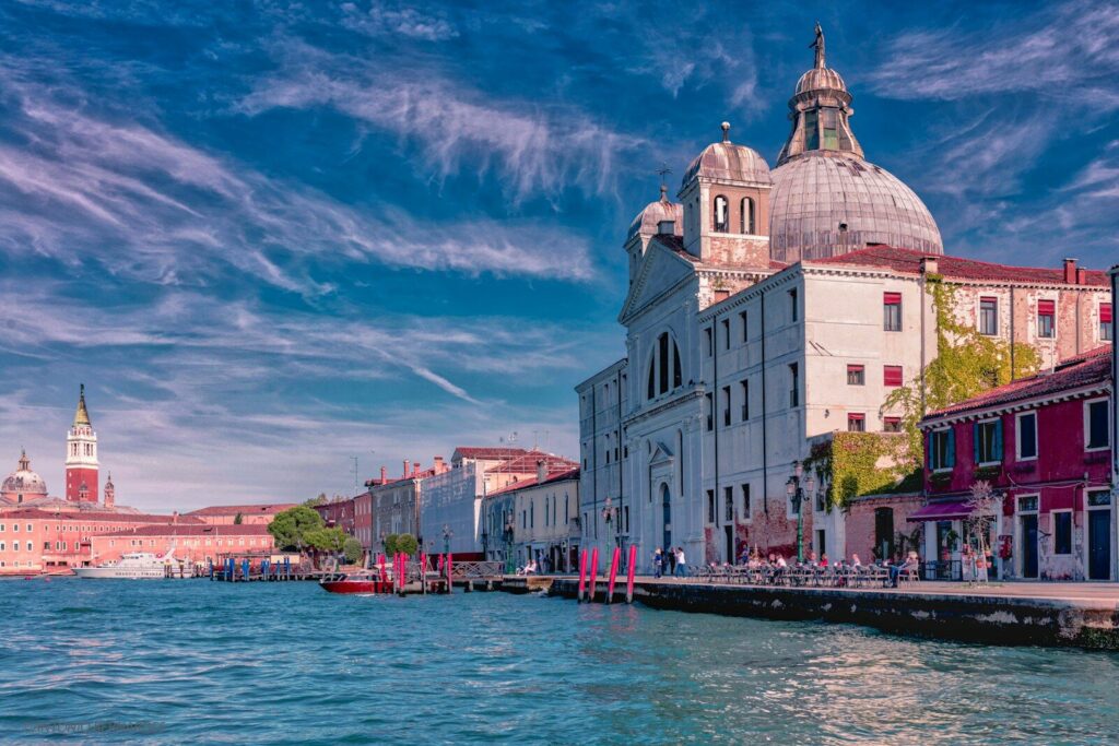 white and brown concrete building beside body of water under blue sky during daytime