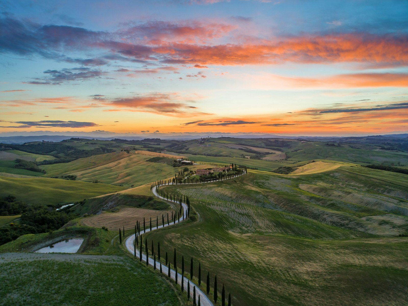 Strada di campagna toscana e colline al tramonto dorato in tarda primavera